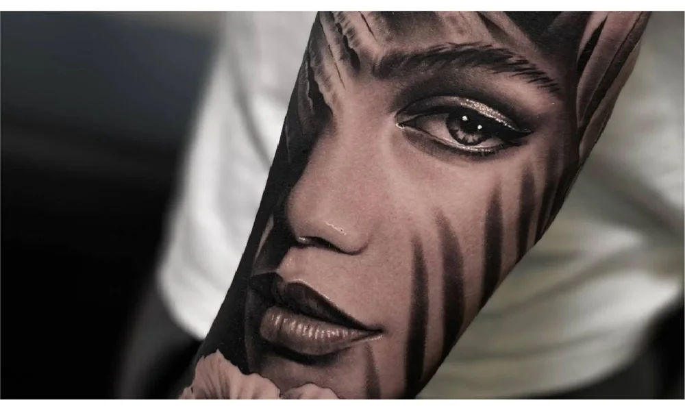 Realistic black-and-grey tattoo portrait of a woman’s face on an arm, showcasing detailed shading for a lifelike effect.