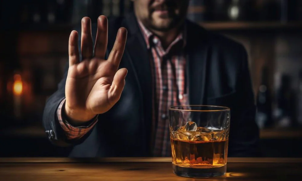 Image of a man signaling to stop with his hand in front of a whiskey glass, emphasising the importance of avoiding alcohol before getting a tattoo.