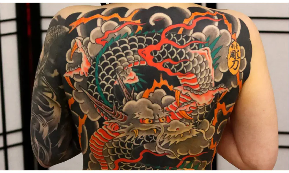 Large Japanese tattoo covering the back, featuring a vibrant dragon surrounded by clouds and traditional Japanese elements.