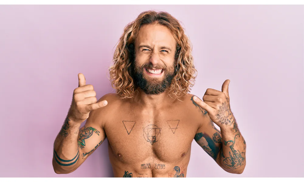 Man with tattoos smiling, showcasing tattoo as self-expression