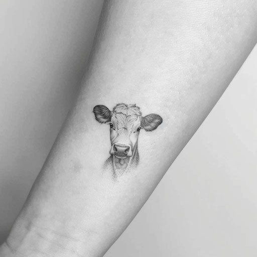 Small minimalist cow tattoo on bright white background