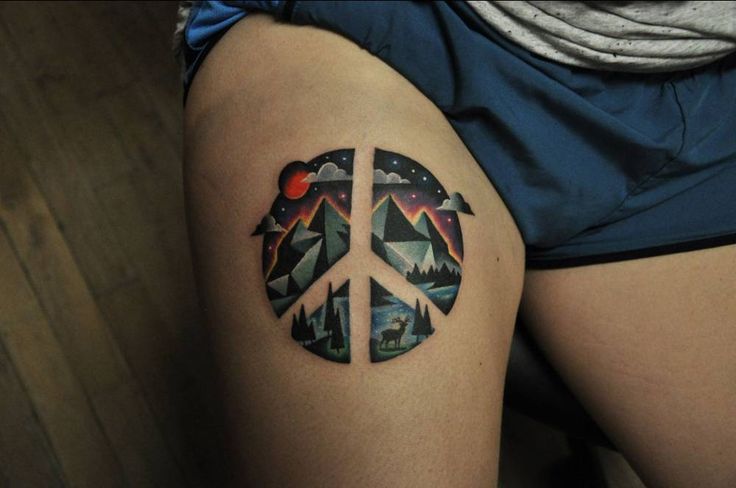 Landscape-peace symbol tattoo on the thigh.