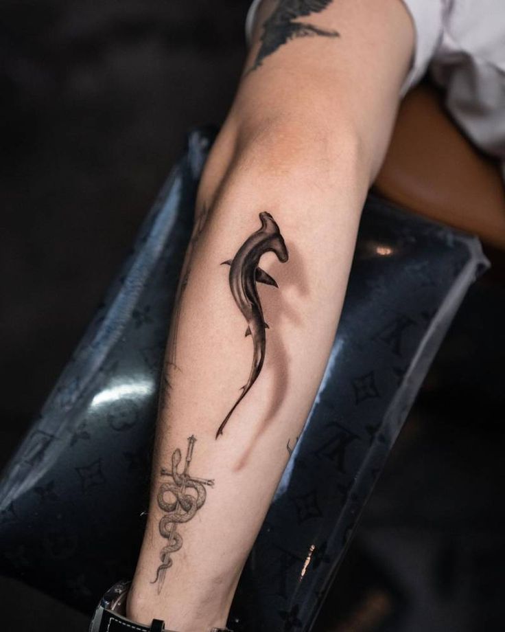 Micro-realistic hammerhead shark tattoo on the forearm.